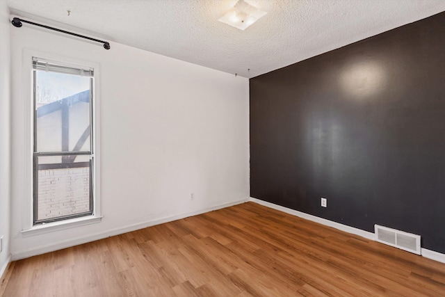 spare room featuring light hardwood / wood-style flooring and a textured ceiling