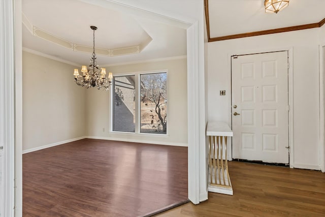 entrance foyer with ornamental molding, dark hardwood / wood-style flooring, a raised ceiling, and a chandelier