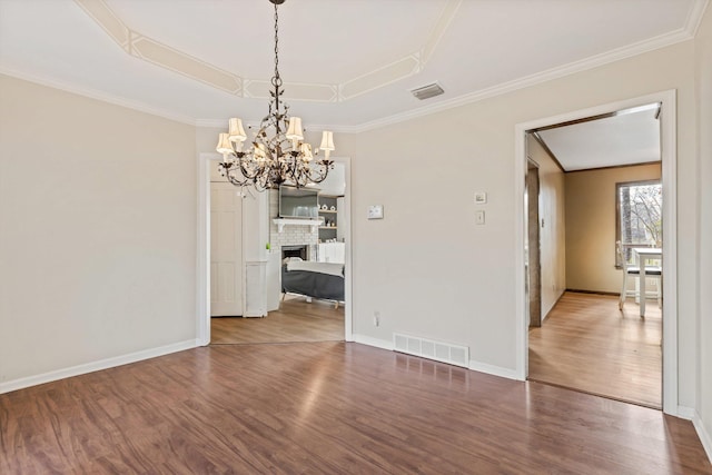 unfurnished dining area featuring wood-type flooring, a fireplace, a tray ceiling, and ornamental molding