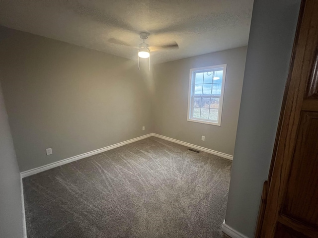 spare room with ceiling fan, a textured ceiling, and dark carpet