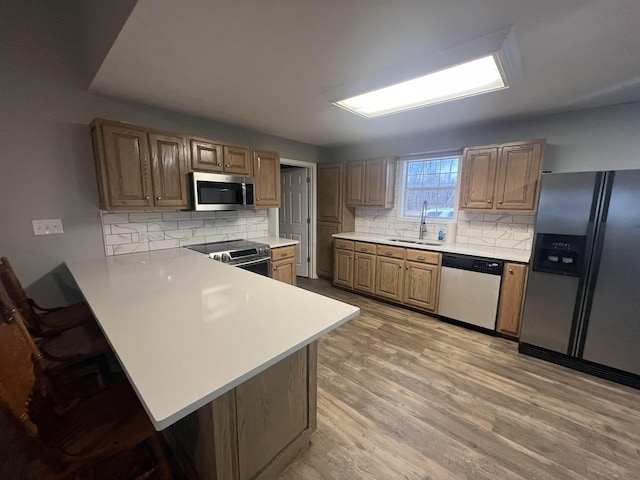 kitchen with kitchen peninsula, sink, decorative backsplash, and appliances with stainless steel finishes