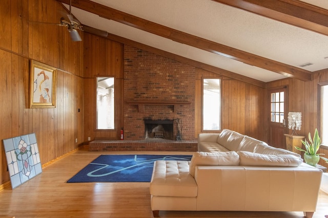 living room featuring wood walls, a brick fireplace, and vaulted ceiling with beams