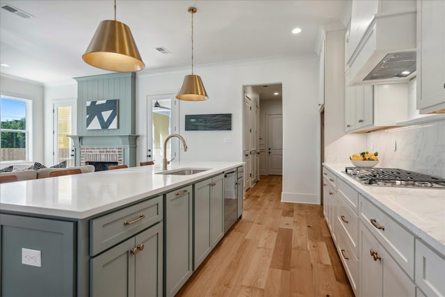 kitchen with appliances with stainless steel finishes, decorative light fixtures, decorative backsplash, sink, and premium range hood