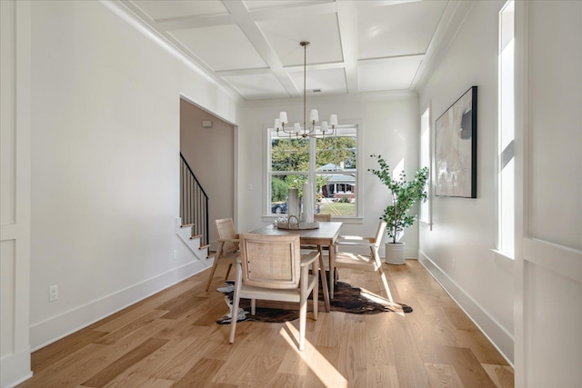 dining space with coffered ceiling, beamed ceiling, an inviting chandelier, and light hardwood / wood-style floors