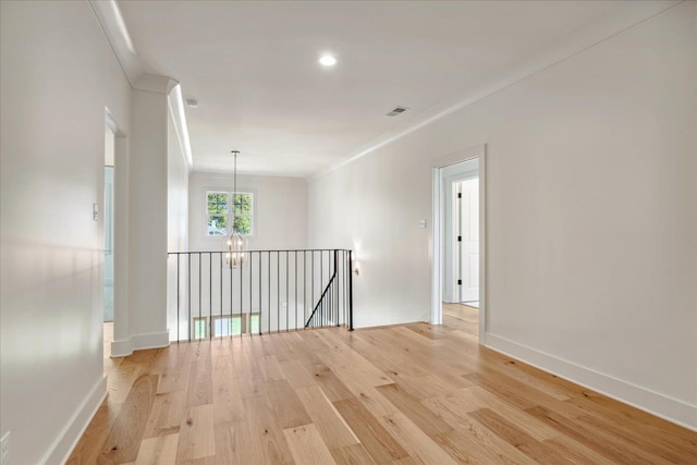 unfurnished room with light hardwood / wood-style flooring, ornamental molding, and a chandelier