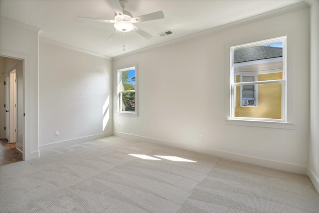 empty room with ceiling fan, light colored carpet, and crown molding