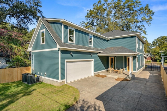 back of house with a garage, cooling unit, a lawn, and a patio