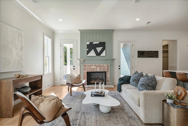 living room with a fireplace, light wood-type flooring, and ornamental molding