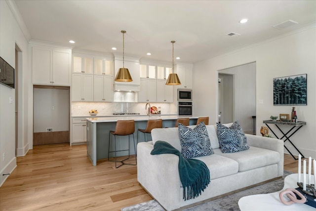 living room featuring sink, light hardwood / wood-style flooring, and ornamental molding