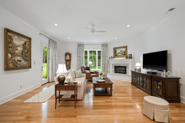 living room featuring a fireplace, light hardwood / wood-style floors, and ceiling fan