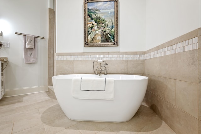 bathroom with tile walls, a bathtub, and tile patterned flooring