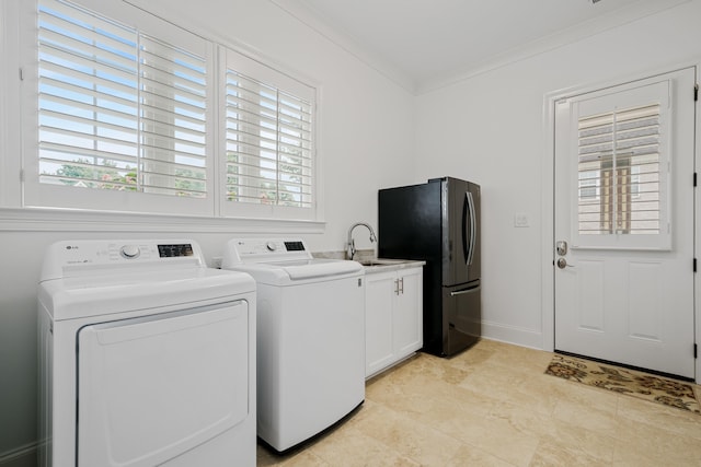 clothes washing area with cabinets, sink, separate washer and dryer, and ornamental molding