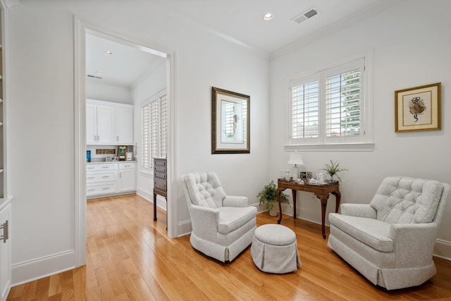 sitting room with light wood-type flooring and ornamental molding