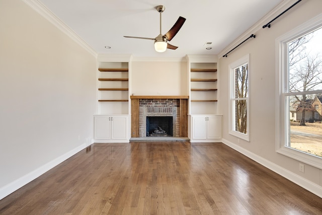 unfurnished living room with ceiling fan, dark hardwood / wood-style floors, a brick fireplace, and ornamental molding