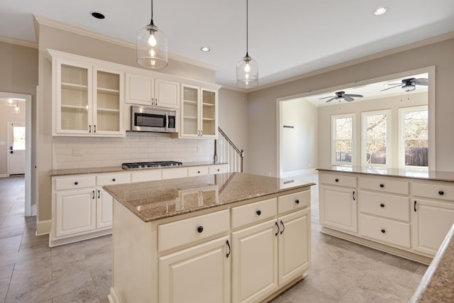 kitchen with decorative light fixtures, a wealth of natural light, stainless steel appliances, and a kitchen island