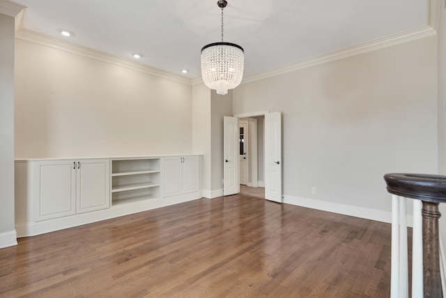 unfurnished living room with a notable chandelier, ornamental molding, dark wood-type flooring, and built in features