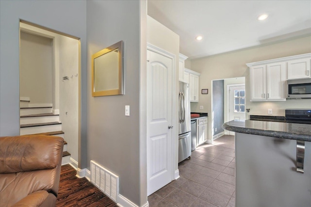 kitchen featuring dark tile patterned flooring, white cabinets, and appliances with stainless steel finishes