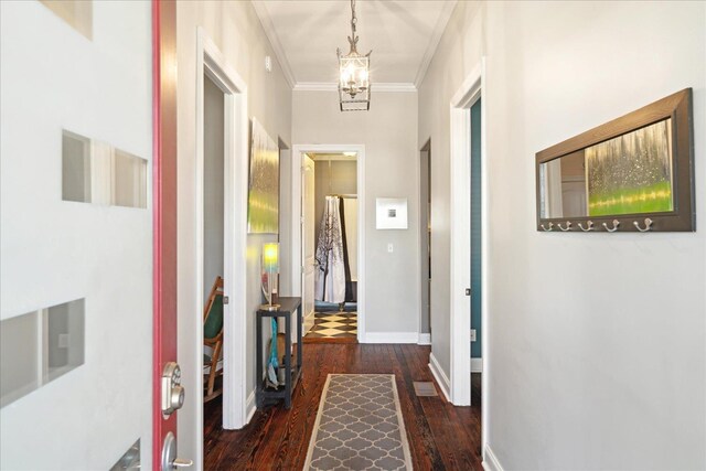 hallway featuring dark hardwood / wood-style floors, ornamental molding, and an inviting chandelier