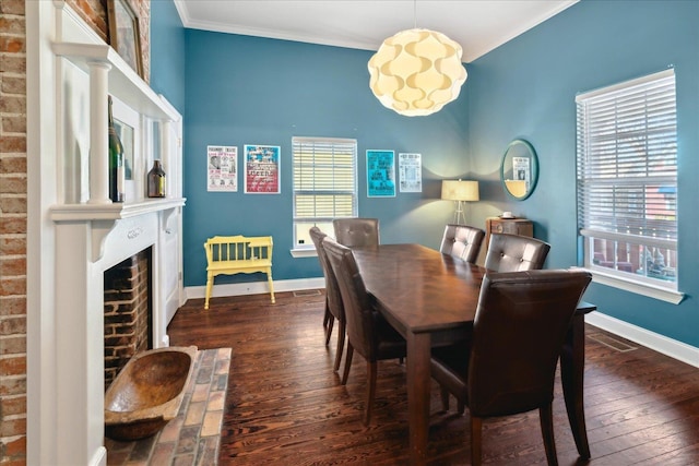 dining area with a brick fireplace, dark wood-type flooring, and crown molding