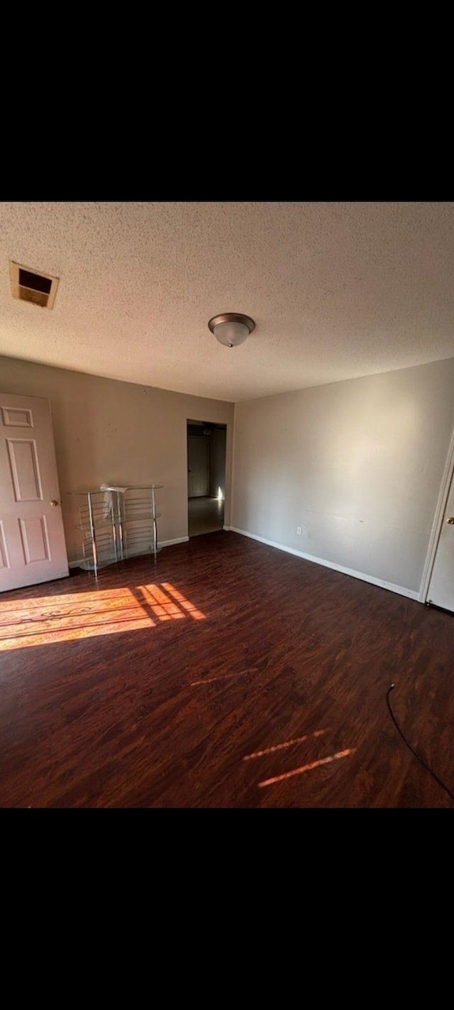 spare room featuring hardwood / wood-style floors and a textured ceiling