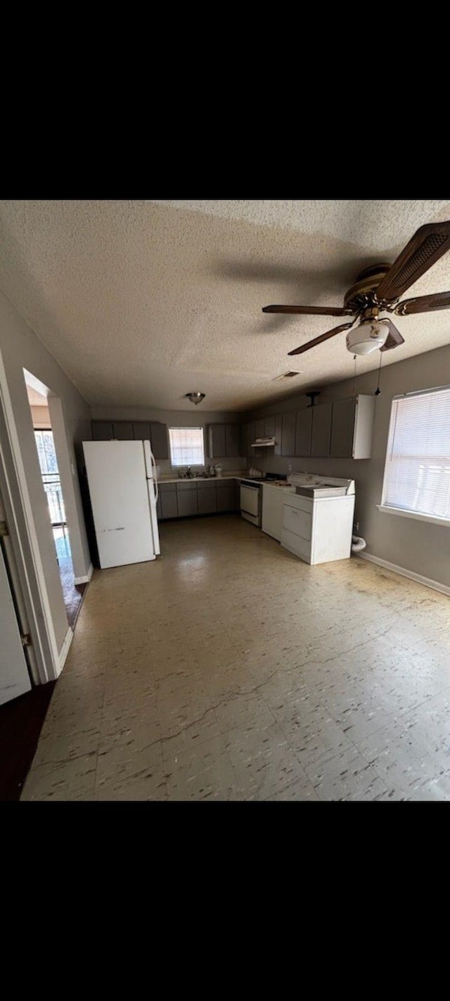 kitchen with ceiling fan, white fridge, and a textured ceiling