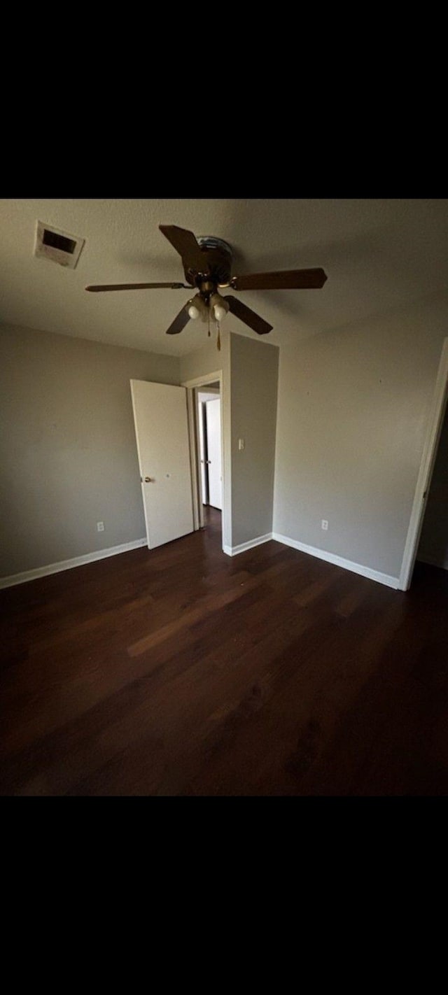 unfurnished room with ceiling fan and dark wood-type flooring