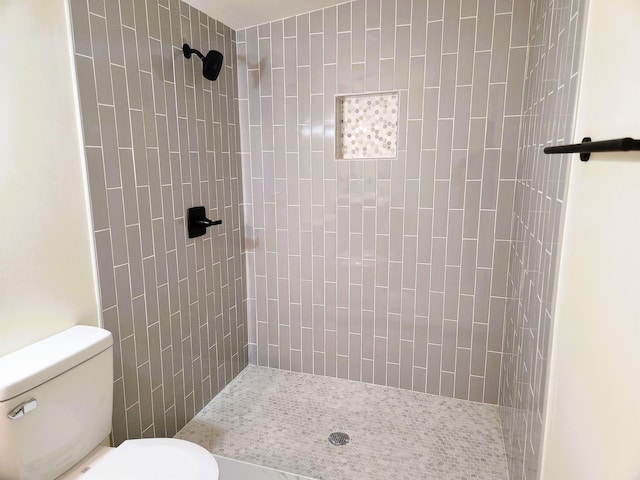 bathroom featuring toilet and a tile shower