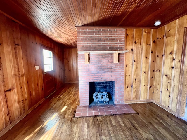 unfurnished living room featuring a fireplace, hardwood / wood-style flooring, and wooden walls