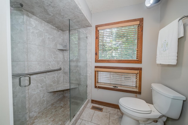 bathroom featuring toilet, a shower with shower door, and tile patterned floors