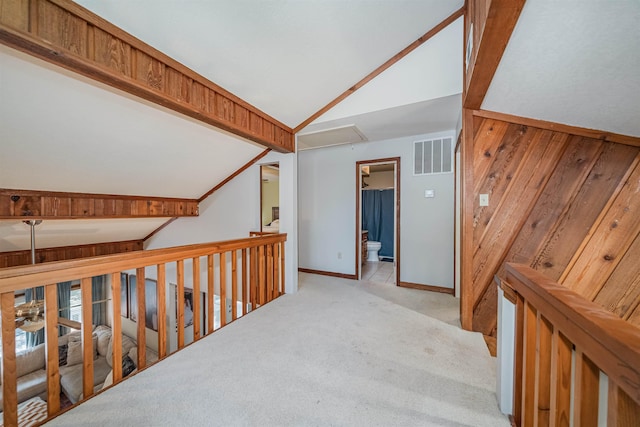 corridor featuring light colored carpet and vaulted ceiling with beams