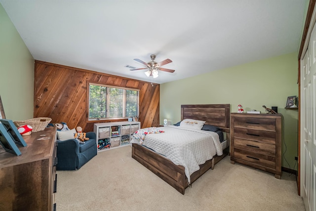 carpeted bedroom featuring ceiling fan, a closet, and wooden walls