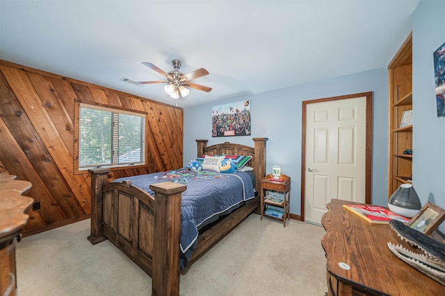 bedroom featuring ceiling fan, light carpet, and wooden walls