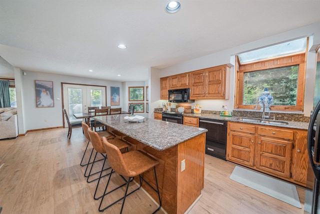 kitchen with black appliances, a kitchen island, light hardwood / wood-style flooring, and sink