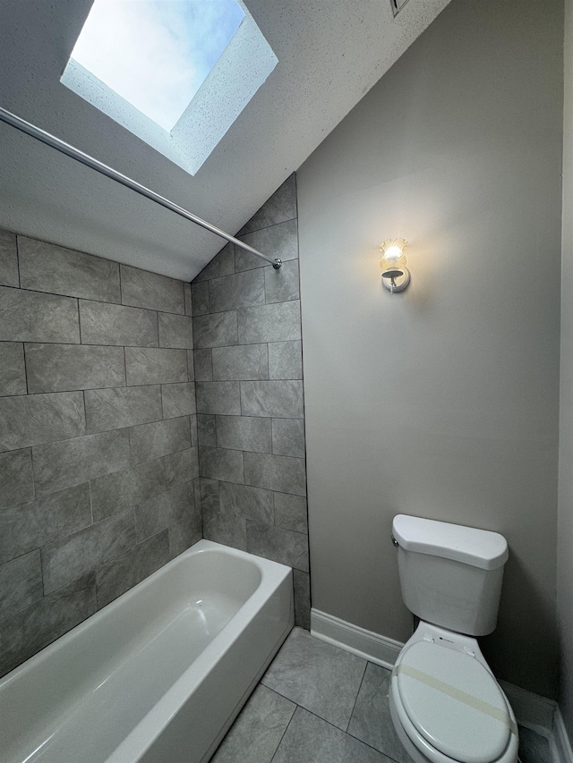 bathroom with toilet, tiled shower / bath, tile patterned flooring, and lofted ceiling with skylight