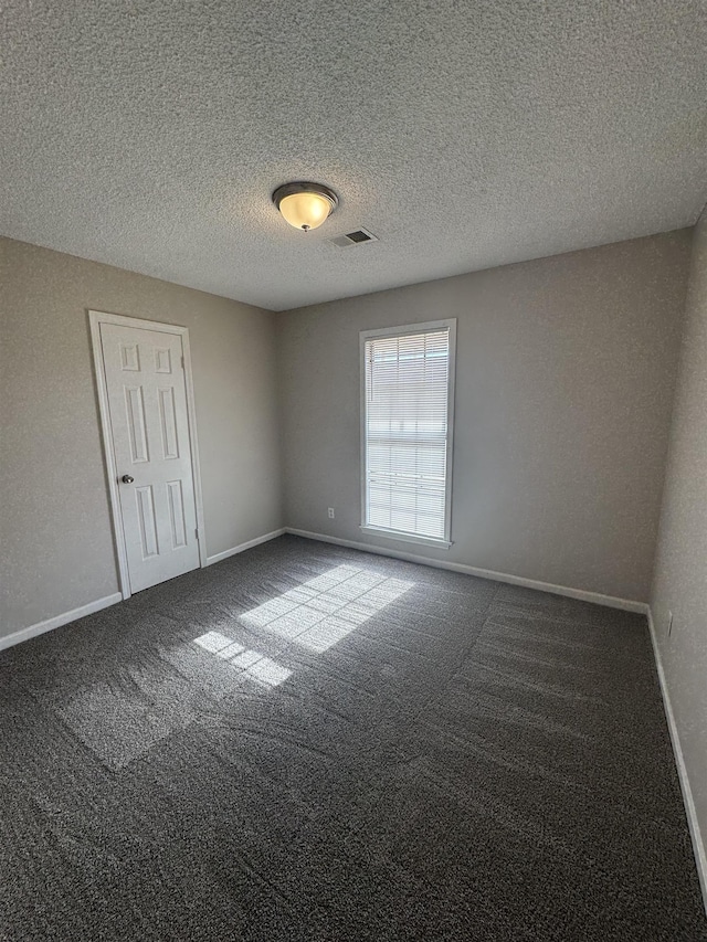 carpeted empty room with a textured ceiling