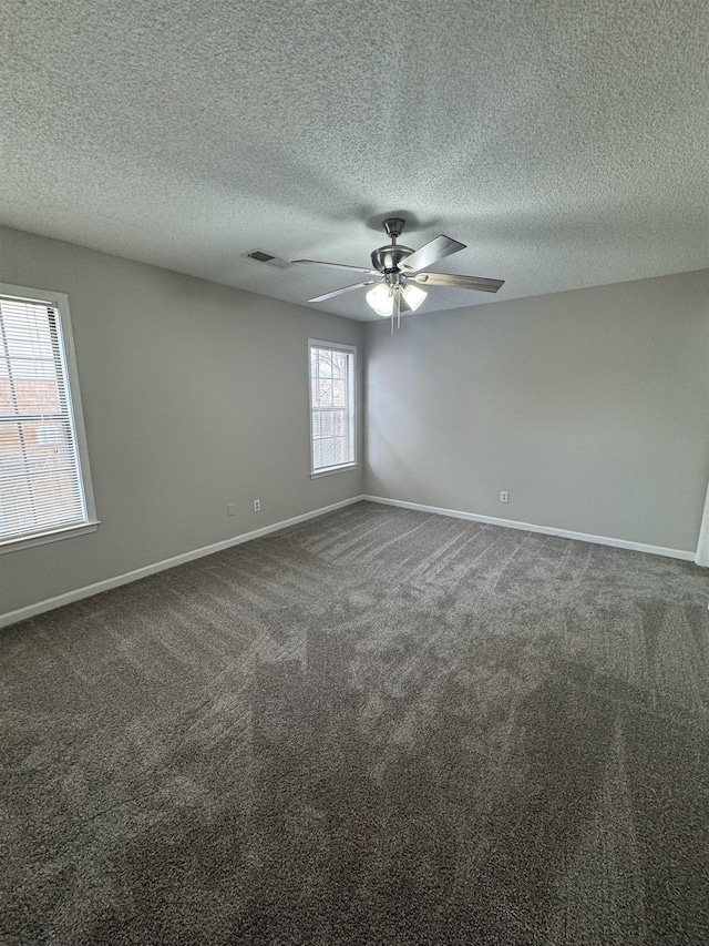 unfurnished room with ceiling fan and dark carpet