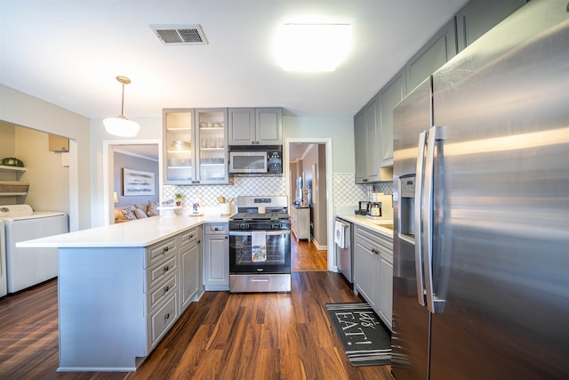 kitchen with decorative light fixtures, independent washer and dryer, backsplash, gray cabinets, and stainless steel appliances