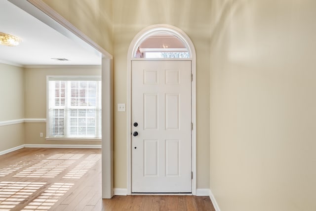 doorway with light wood-type flooring and ornamental molding