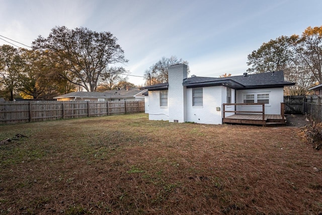 back of property with a wooden deck and a lawn