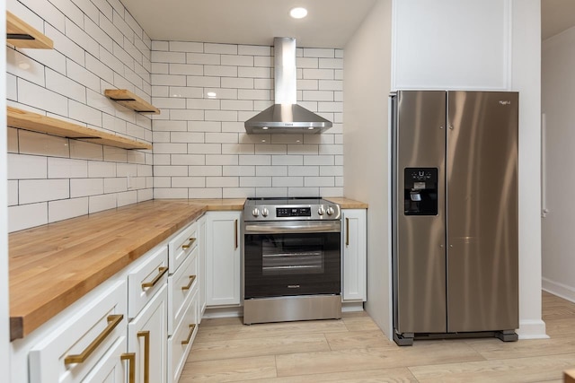 kitchen featuring wall chimney exhaust hood, backsplash, white cabinetry, butcher block countertops, and stainless steel appliances