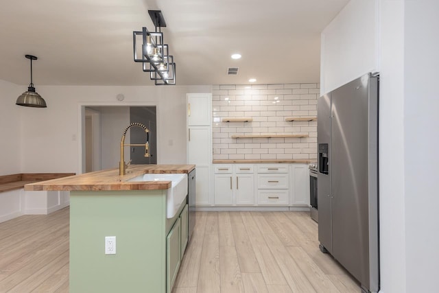 kitchen with white cabinets, sink, decorative light fixtures, stainless steel appliances, and wood counters