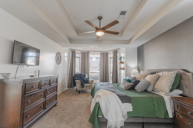 carpeted bedroom with ceiling fan and a raised ceiling