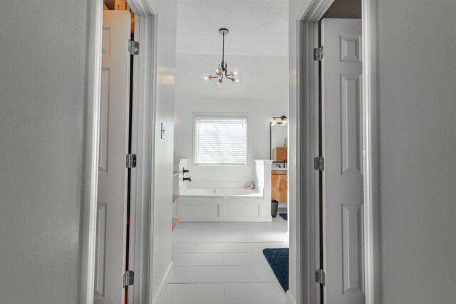 corridor with a notable chandelier and light tile patterned flooring