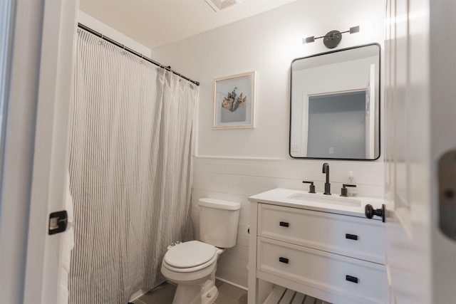 bathroom with tile walls, toilet, vanity, and a textured ceiling