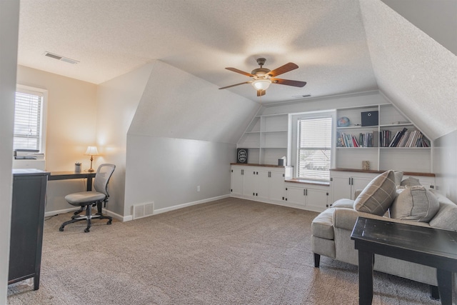 interior space with light carpet, built in shelves, a textured ceiling, and lofted ceiling