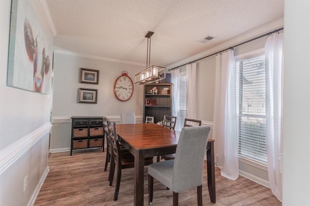 dining area with ornamental molding, hardwood / wood-style floors, and a textured ceiling