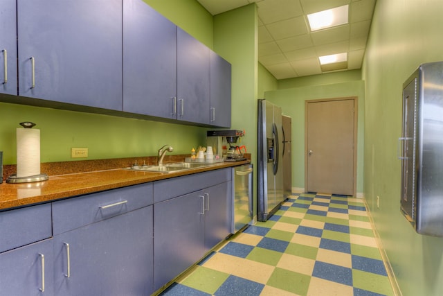 kitchen featuring sink, a drop ceiling, dark stone countertops, and appliances with stainless steel finishes