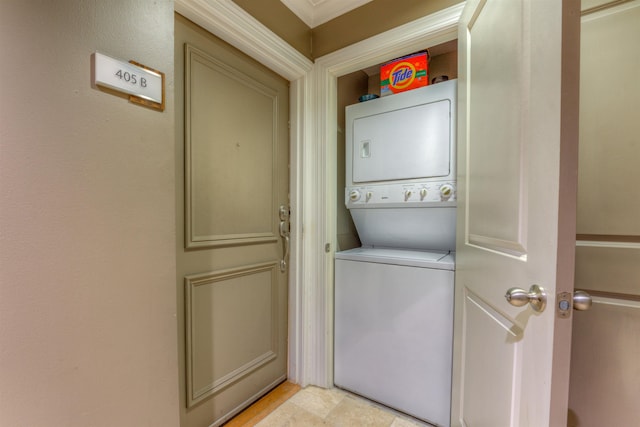 clothes washing area featuring stacked washer / drying machine and crown molding