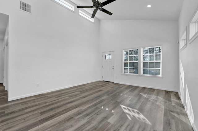 interior space with ceiling fan, dark wood-type flooring, and a towering ceiling