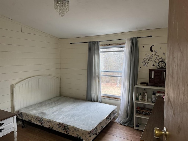 bedroom featuring lofted ceiling, dark wood-type flooring, and wooden walls